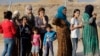 FILE - Syrians who were displaced by fighting in northeastern Syria line up to receive aid and food at the Bardarash refugee camp north of Mosul, Iraq, on Oct. 17, 2019. Human Rights Watch on June 27, 2024, called on Iraq to stop deporting refugees back to Syria.
