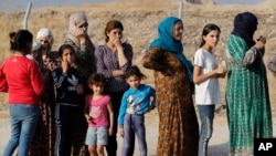 Syrian women who were displaced by the Turkish military operation in northeastern Syria line up to receive aid and food supplies, at the Bardarash refugee camp, north of Mosul, Iraq, Thursday, Oct. 17, 2019.