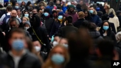 FILE - Shoppers wearing face coverings walk down Oxford Street, Europe's busiest shopping street, in London, Dec. 23, 2021. 