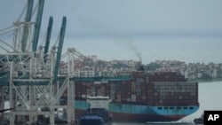 资料照片：一艘集装箱货轮在拖船引导下进入迈阿密港。(2021年10月21日)