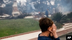 A woman cries as she covers her face near her destroyed home after a wildfire swept through Ventura, Calif., Dec. 5, 2017.