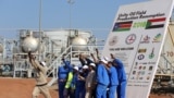 Workers take a photo during a ceremony marking the restarting of crude oil pumping at the Unity oil fields in South Sudan, January 21, 2019. Picture taken January 21, 2019. REUTERS/Samir Bol - RC150EBBFA70