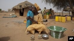 FILE - Maryam Sy comforts her two-year-old son Aliou Seyni Diallo, the youngest of nine, after a neighbor gave him dry couscous to stop him from crying from hunger, May 1, 2012. 