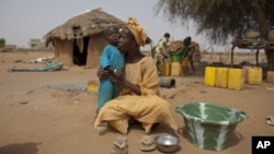 FILE - Maryam Sy comforts her 2-year-old son Aliou Seyni Diallo, the youngest of nine, after a neighbor gave him dry couscous to stop him from crying with hunger, May 1, 2012. 