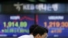 A currency trader watches the computer monitors near the screens showing the Korea Composite Stock Price Index (KOSPI), left, and the foreign exchange rate between U.S. dollar and South Korean won at the foreign exchange dealing room in Seoul, South Korea.