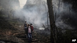 Residentes caminan en un área carbonizada por un incendio forestal en Nemocón, al norte de Bogotá, Colombia, el martes 23 de enero de 2024.