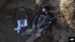 Un soldado de la primera brigada Bureviy (Huracán) de la Guardia Nacional de Ucrania se sienta en una trinchera durante un entrenamiento de combate en un campo de entrenamiento militar en el norte de Ucrania el viernes 3 de noviembre de 2023.