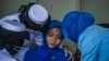 Military personnel console a sailor's wife during a remembrance ceremony for the crew of the Indonesian navy submarine KRI Nanggala that sank on April 21 during a training exercise, on the deck of the hospital ship KRI Dr. Soeharso off the coast of Bali.