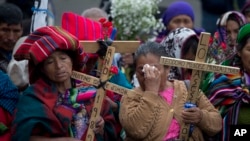 ARCHIVO - Mujeres indígenas rezan sosteniendo cruces de madera durante una ceremonia en honor de activistas de derechos humanos frente a la Corte Suprema en Ciudad de Guatemala. Feb. 25, 2016.