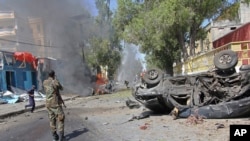 Seorang tentara Somalia berdiri di dekat mobil yang hancur akibat ledakan bom di Mogadishu Somalia, 1 Oktober 2016 (AP Photo/Farah Abdi Warsameh).