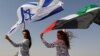 Modelja izraelite May Tager, mban flamurin izraelit, ndërsa pozon me modelen nga Dubai, Anastasia, me një flamur të Emirateve (Dubai, 8 shtator 2020).