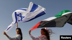 FILE - Israeli model May Tager, holding an Israeli flag, poses with Dubai-resident model Anastasia, holding an Emirati flag, during a photoshoot for FIX's Princess Collection in Dubai, UAE, Sept. 8, 2020.