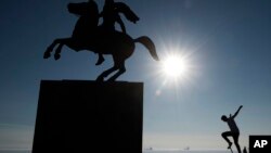 A skateboarder practices next to the modern bronze statue of Alexander the Great on his horse Bucephalus in the northern port city of Thessaloniki, Greece, Jan. 30, 2018. Parts of the city have been without water for five days because of a failed water pipe.