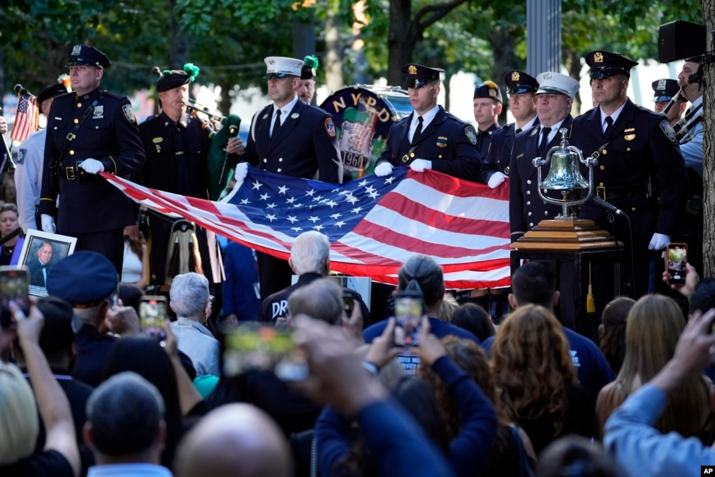 Una guardia de honor de la Policía de Nueva York, sostuvo la bandera de Estados Unidos durante el homenaje en la Zona Cero, lugar donde hace 23 años estaban los dos rascacielos y que ahora alberga monumentos con los nombres de las personas asesinadas. 