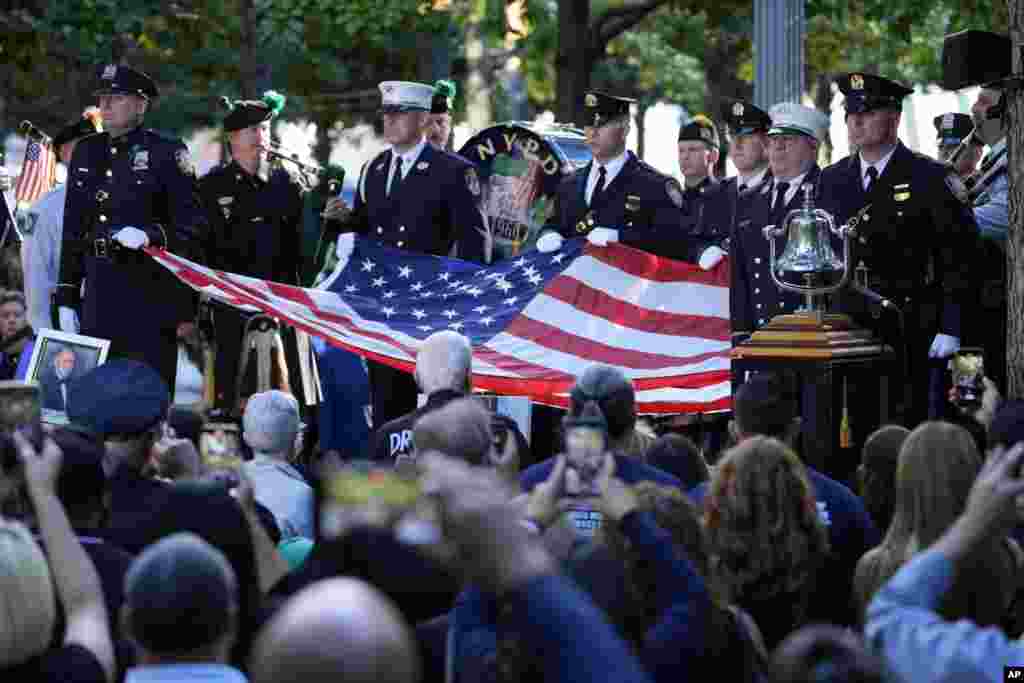 Una guardia de honor de la Policía de Nueva York, sostuvo la bandera de Estados Unidos durante el homenaje en la Zona Cero, lugar donde hace 23 años estaban los dos rascacielos y que ahora alberga monumentos con los nombres de las personas asesinadas.&nbsp;