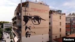 FILE - A giant mural depicts Italian composer Ennio Morricone created by Asterios Laskaris, Christos Laskaris and Dimitra Kalogirou under the auspices of the Greek Cultural Association Friends of Ennio Morricone's Music, in Larissa, Greece, July 24, 2018.