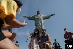 Turistas disfrutan de una visita a la estatua del Cristo Redentor, en el Cerro Corcovado, en Río de Janeiro, Brasil, el 15 de agosto de 2020, durante el día de reapertura de las atracciones turísticas de la ciudad en medio de la pandemia del Covid.