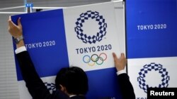 A staff takes out a banner featuring Tokyo 2020 Olympics emblem from the wall after a news conference hosted by International Olympic Committee (IOC) Vice President John Coates and President of Tokyo 2020 Olympic and Paralympic organizing committee Yoshiro Mori in Tokyo, Japan June 30, 2017.