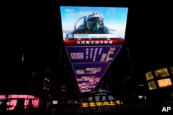 FILE - An outdoor screen depicts a Chinese fighter jet pilot giving a thumbs up in the recently concluded Joint Sword exercise around Taiwan during the evening news broadcast in Beijing, April 10, 2023.