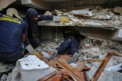 Firefighters search for survivors inside a collapsed building, after Saturday´s 7.2 magnitude earthquake in Les Cayes, Haiti, Aug. 15, 2021.
