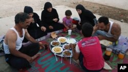 Syrian refugee family members break their fasting outside their tent at a refugee camp in the eastern town of Marj in Bekaa valley, Lebanon, June 29, 2014. 