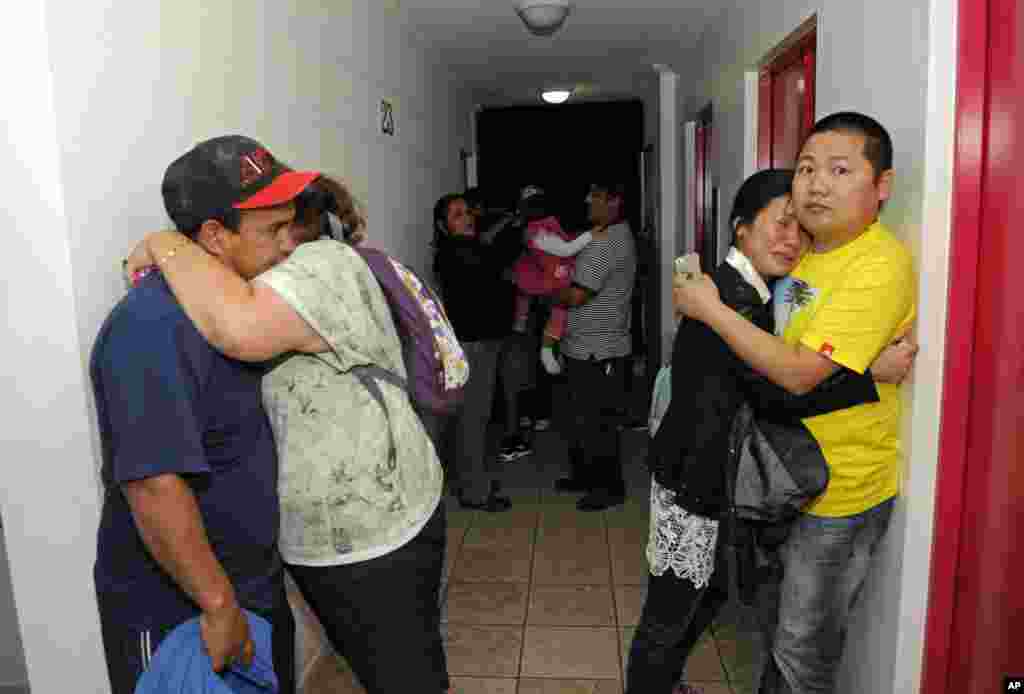 People embrace on the upper floor of an apartment building located a few blocks from the coast where they gathered to avoid a possible tsunami after a powerful magnitude-8.2 in Iquique, Chile, Apr. 1, 2014.