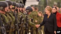 FILE - German chancellor Angela Merkel shakes hands with soldiers during a visit of the German Army medical service in Leer, northern Germany, Dec. 7, 2015. 