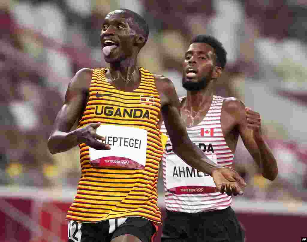 Joshua Cheptegei, of Uganda, leads Mohammed Ahmed, of Canada, silver, to win the gold medal in the final of the men's 5,000-meters at the 2020 Summer Olympics, Friday, Aug. 6, 2021, in Tokyo, Japan. (AP Photo/Charlie Riedel)