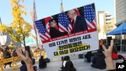 Seorang pengunjuk rasa mengangkat spanduk bergambar Presiden AS Donald Trump dan pemimpin Korea Utara Kim Jong-un dalam unjuk rasa menentang kebijakan AS untuk memberikan tekanan yang stabil terhadap Korea Utara di dekat Kedutaan Besar AS di Seoul, Korea Selatan, Sabtu, November. 3, 2018.