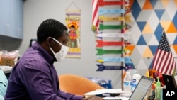 Teaching assistant Samuel Lavi helps out with an online class at the Valencia Newcomer School for refugees who speak a variety of languages and are learning to use technology like iPads and messaging apps, Sept. 2, 2020.