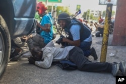 Journalists take cover from the exchange of gunfire between gangs and police in Port-au-Prince, Haiti, Nov. 11, 2024.