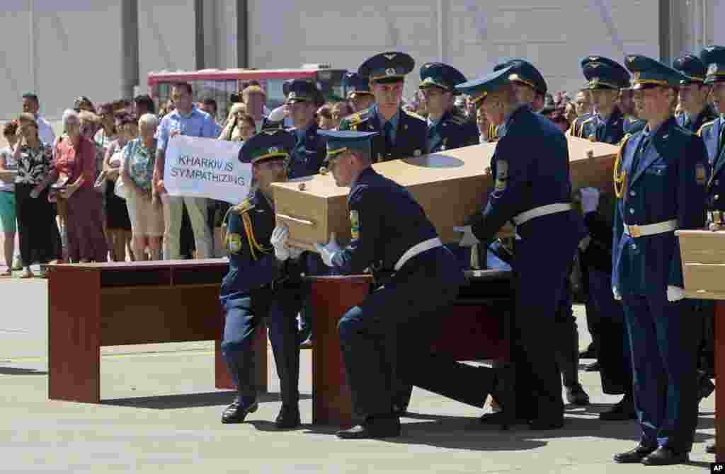 Ukrainian honor guards lift up a coffin containing the body of a Malaysian Airlines plane passenger to load it on a Dutch cargo plane, in Kharkiv Airport, Ukraine, July 23, 2014.