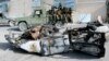 Somali soldiers sit on a pickup truck near the wreckage of a car bomb that was detonated at the main gate of the presidential palace in Mogadishu, July, 9, 2014.