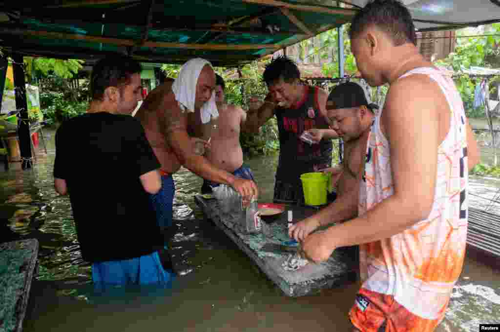 Watu wanakula na kunywa barabarani katika mji wa Balagtas, jimbo la Bulacan, nchini Ufilipino kufuatia mafuriko yaliyotokana na mvua nyingi zilizosababishwa na kimbunga Doksuri.