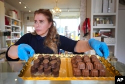 FILE—Niaz Mardan moves a tray of luxury handmade Belgian chocolates at Sandrine a chocolate shop in south west London, March 21, 2024.