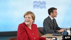 Germany's Chancellor Angela Merkel and France's President Emmanuel Macron sit at the table at the start of the G-7 summit in Carbis Bay, Cornwall, on June 11, 2021.
