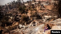 A resident whose home was destroyed by a major fire sits amid the destruction in Valparaiso, Chile, April 13, 2014. 