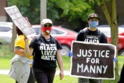 FILE - A protester holds a sign that reads "Justice for Manny" during a protest against police brutality, in Tacoma, Wash., June 5, 2020.