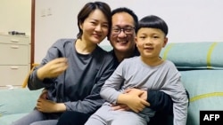 This handout photo taken on April 27, 2020 and released by Wang Qiaoling, shows human rights lawyer Wang Quanzhang (C) embracing his wife Li Wenzu and their son after they were reunited in Beijing, China.