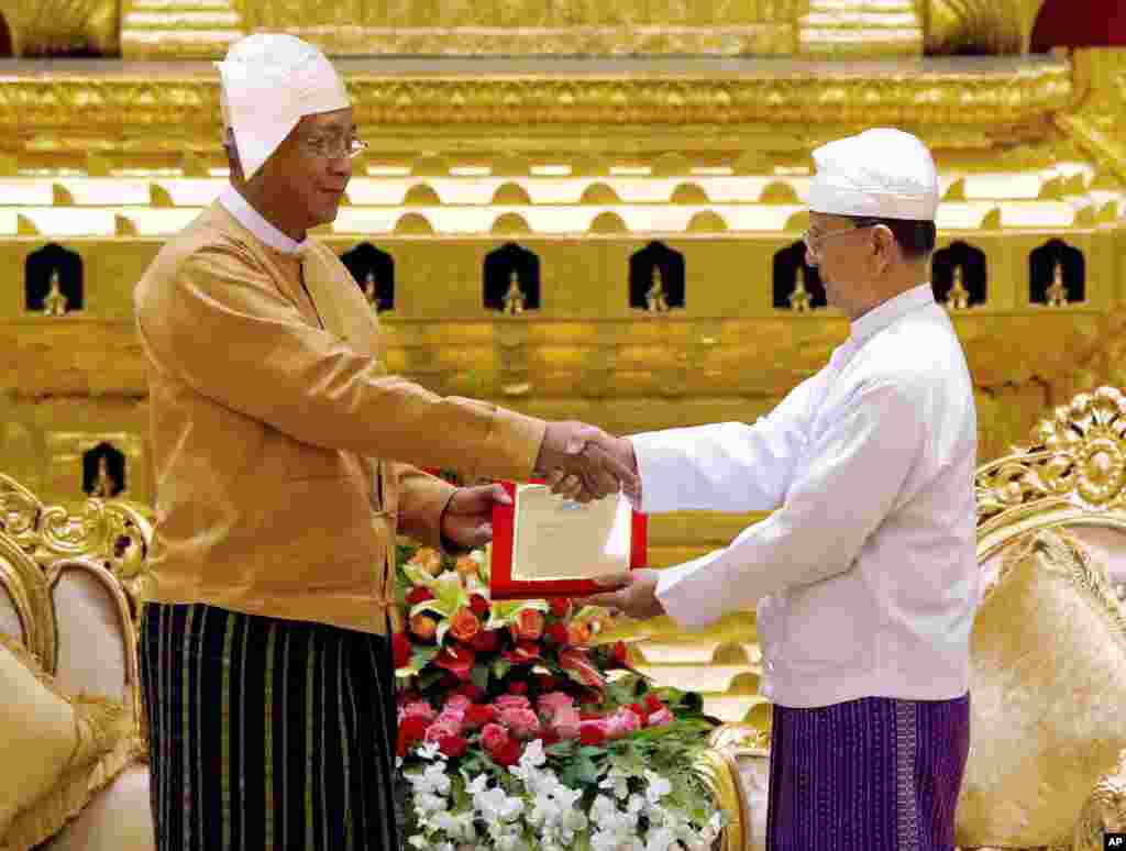 Myanmar&#39;s new president Htin Kyaw, left, receives the presidential seal from outgoing president Thein Sein, during a handover ceremony in Naypyitaw, March 30, 2016.