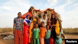 A family stands beside their shelter at a camp for internally displaced people from drought hit areas in Dollow, Somalia, April 3, 2017. 