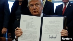 U.S. President Donald Trump signs a memorandum to security services directing them to defeat the Islamic State in the Oval Office at the White House in Washington, Jan. 28, 2017. 