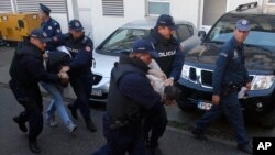 Montenegrin police officers escort men for questioning, in Podgorica, Montenegro, Oct. 16, 2016, as the small Balkan country held parliamentary elections.