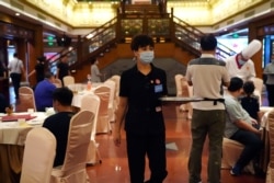 A staff member who is also an anti-food waste supervisor, holds a tray at the Quanjude Roast Duck restaurant, following the coronavirus disease (COVID-19) outbreak in Beijing, Aug. 18, 2020.