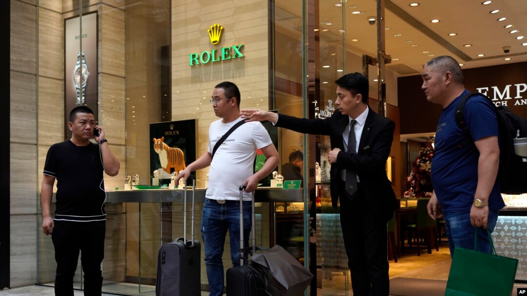 FILE - In this Oct. 30, 2019 photo, a salesman of a watch shop directs the way to find a taxi for a group of mainland tourists in a shopping district in Hong Kong. 