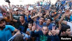 Migranti mašu svojim voznim kartama ispred Istočne železničke stanice u Budimpešti, Mađarska 1. septembar 2015.