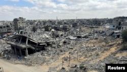 Palestinians walk past the rubble of houses destroyed in Israel's military offensive, amid the ongoing conflict between Israel and Hamas, in Khan Younis in the southern Gaza Strip, Oct. 7, 2024