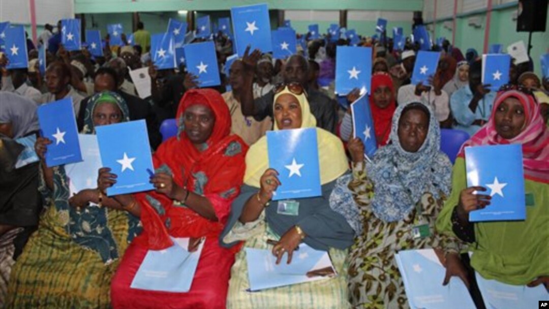 Somalia's constituency assembly members hold up copies of the proposed new constitution during the beginning of a nine-day meeting in Mogadishu, July 25, 2012.