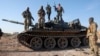 (FILE) Syrian opposition fighters stand atop a seized military armored vehicle on the outskirts of Hama, Syria, Tuesday, Dec. 3, 2024.