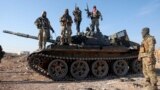 (FILE) Syrian opposition fighters stand atop a seized military armored vehicle on the outskirts of Hama, Syria, Tuesday, Dec. 3, 2024.